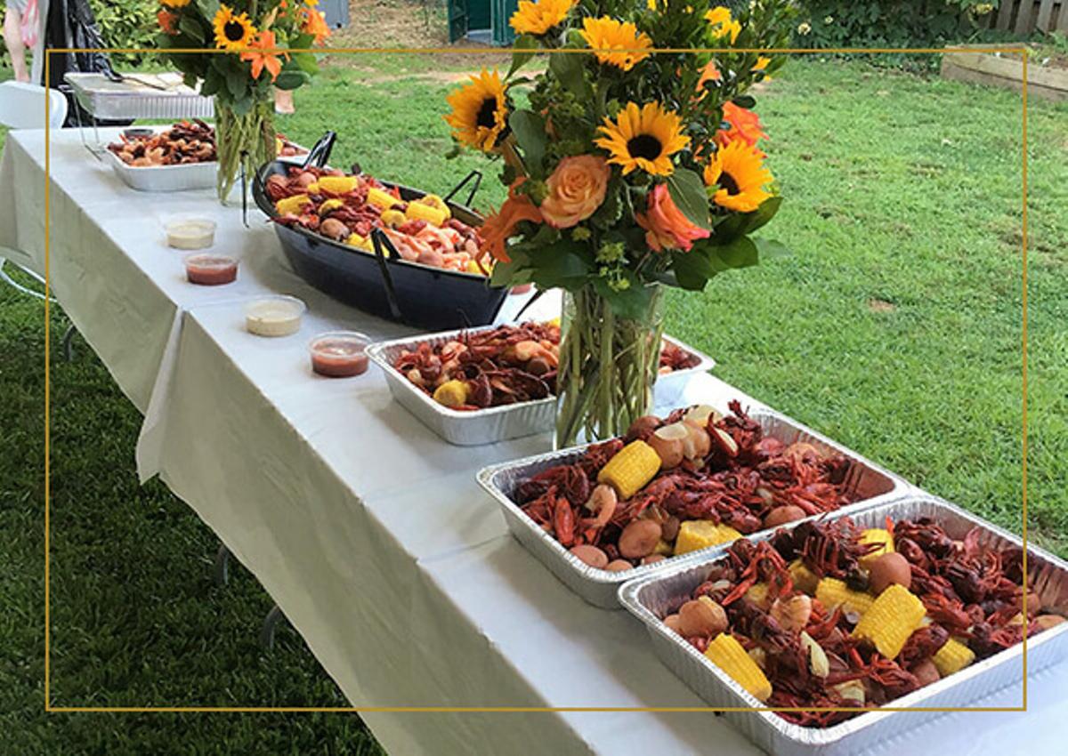 A catered outdoor event with fresh boiled corn, potatoes, and crawfish